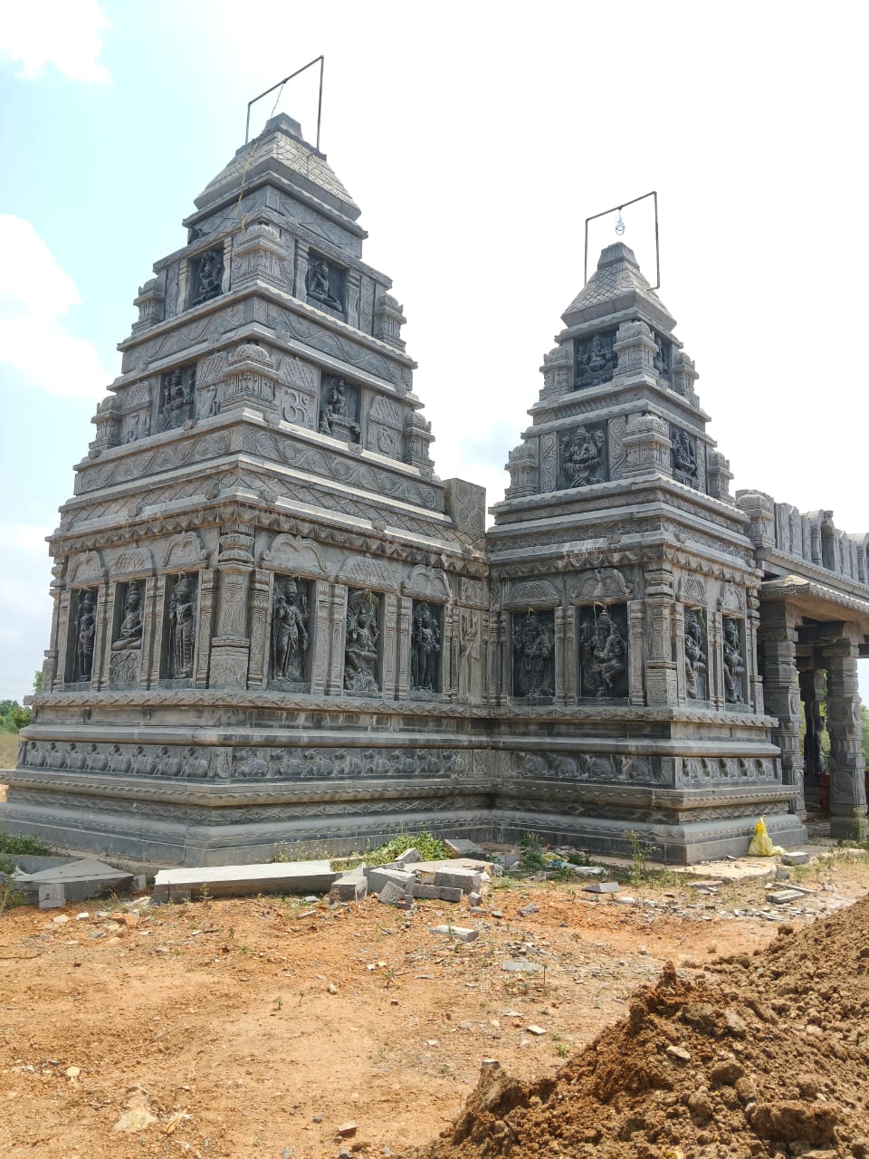 Twin carved stone towers of the Shivalayam under construction